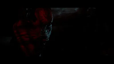 Twisted creature standing in red light in a Townfall corridor